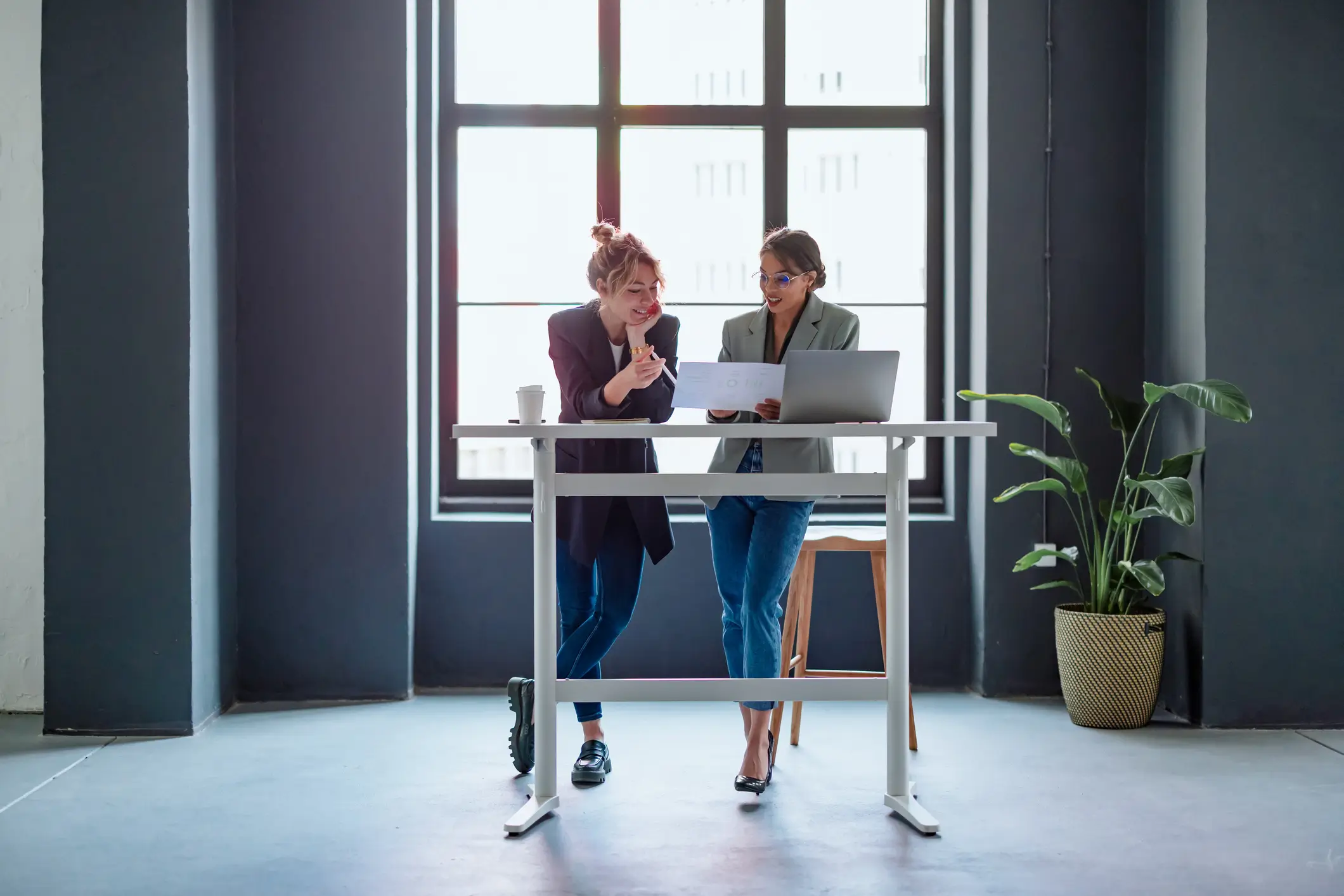 Two business women discussing plans over standing desk