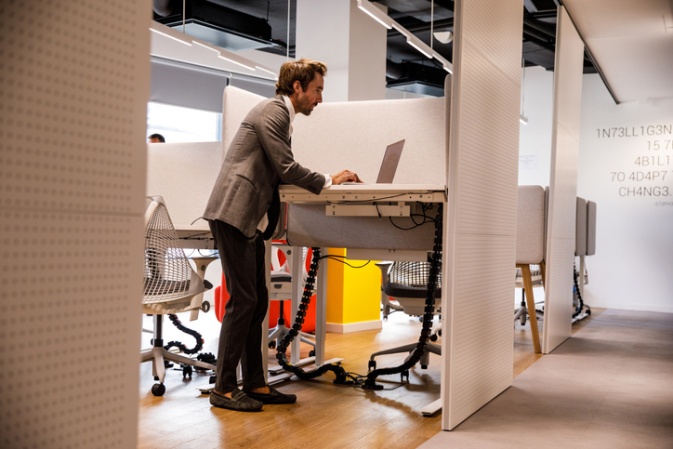 A Professional Man at a White Height-Adjustable Standing Desk with Privacy Screens in Atlanta, GA