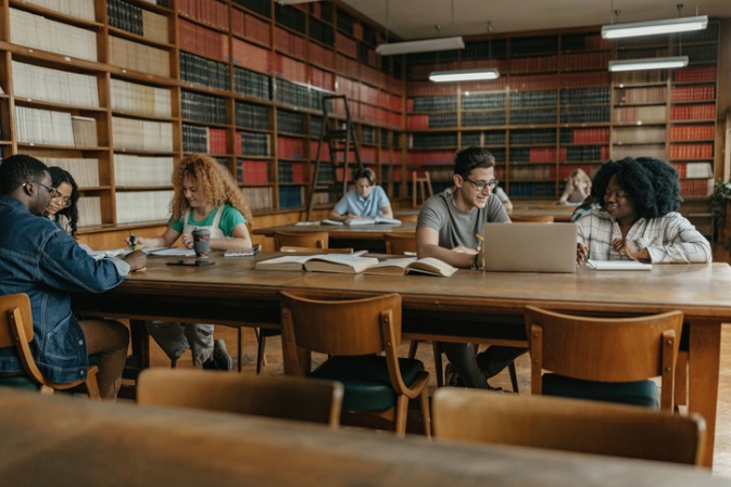 Students working together at large, shared tables in a collaborative library area